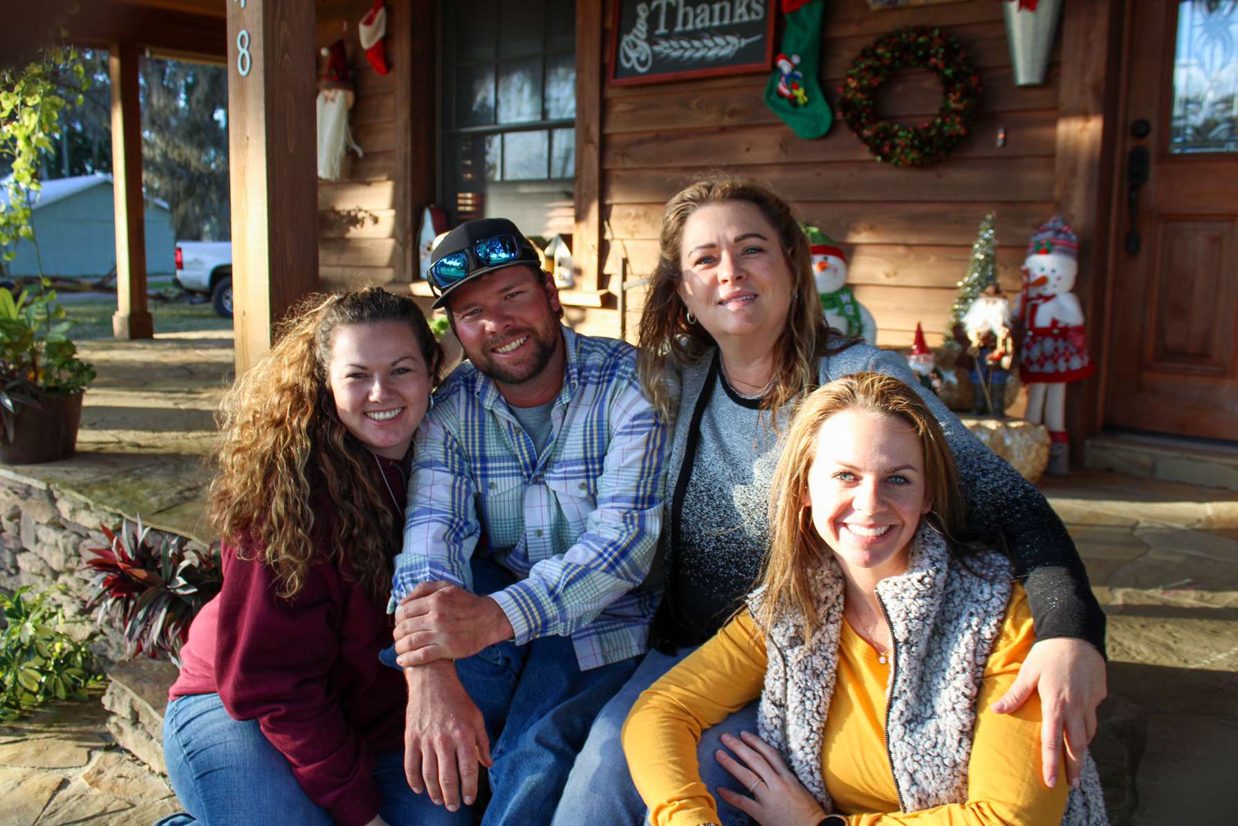 A group of people sitting on the porch of a log cabin.