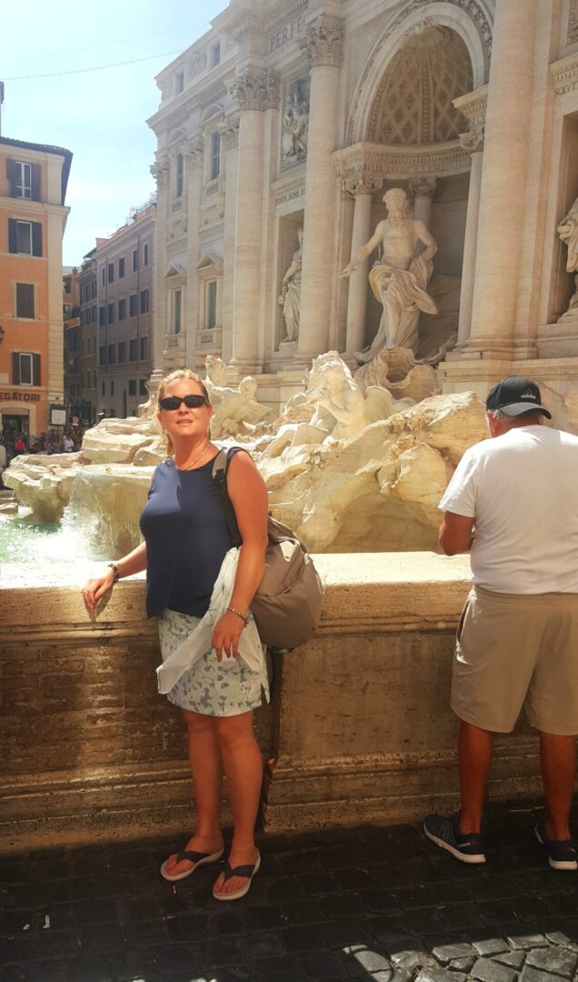A woman standing in front of the trevi fountain.