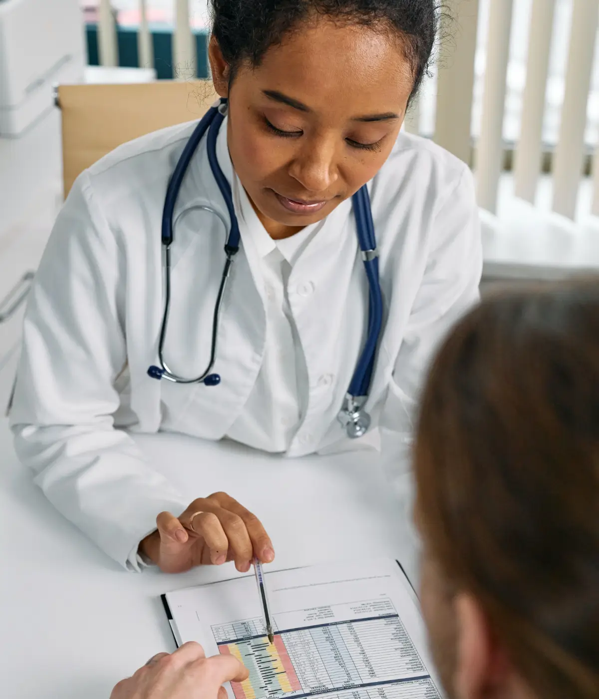 A doctor is sitting at the table and looking at a patient.